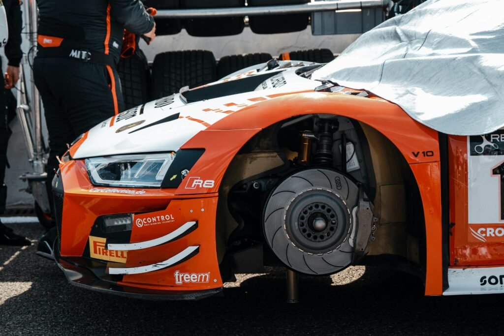 Close-up of a racing car wheel being repaired at a pit stop with mechanics working.