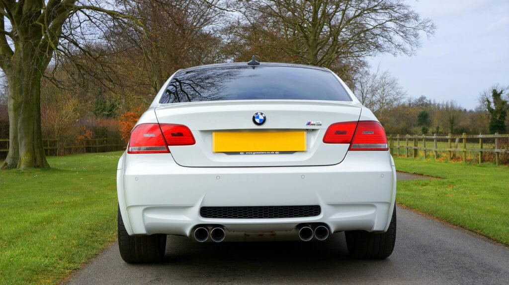 pexels-photo-7663126-7663126 Elegant white BMW M3 parked on a scenic countryside road in the UK, emphasizing rear design and lush surroundings.